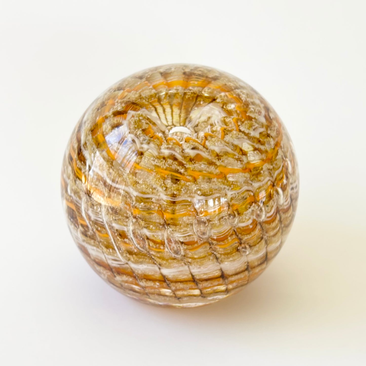 Swirled cremation glass art with ashes encased in ridged ripple pattern and optic bubble center
