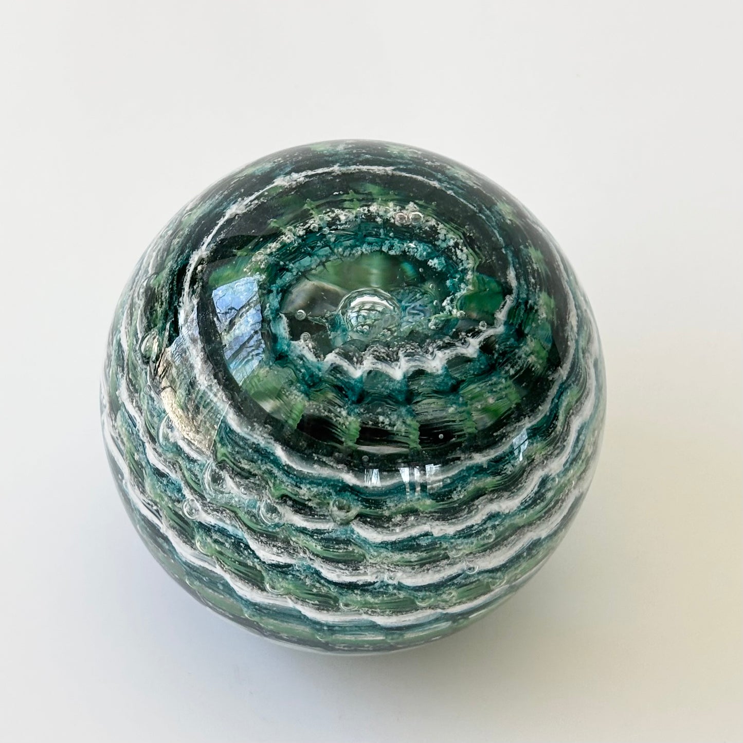 Hand-blown cremation glass sphere with ashes swirled in ripple pattern for pets or people
