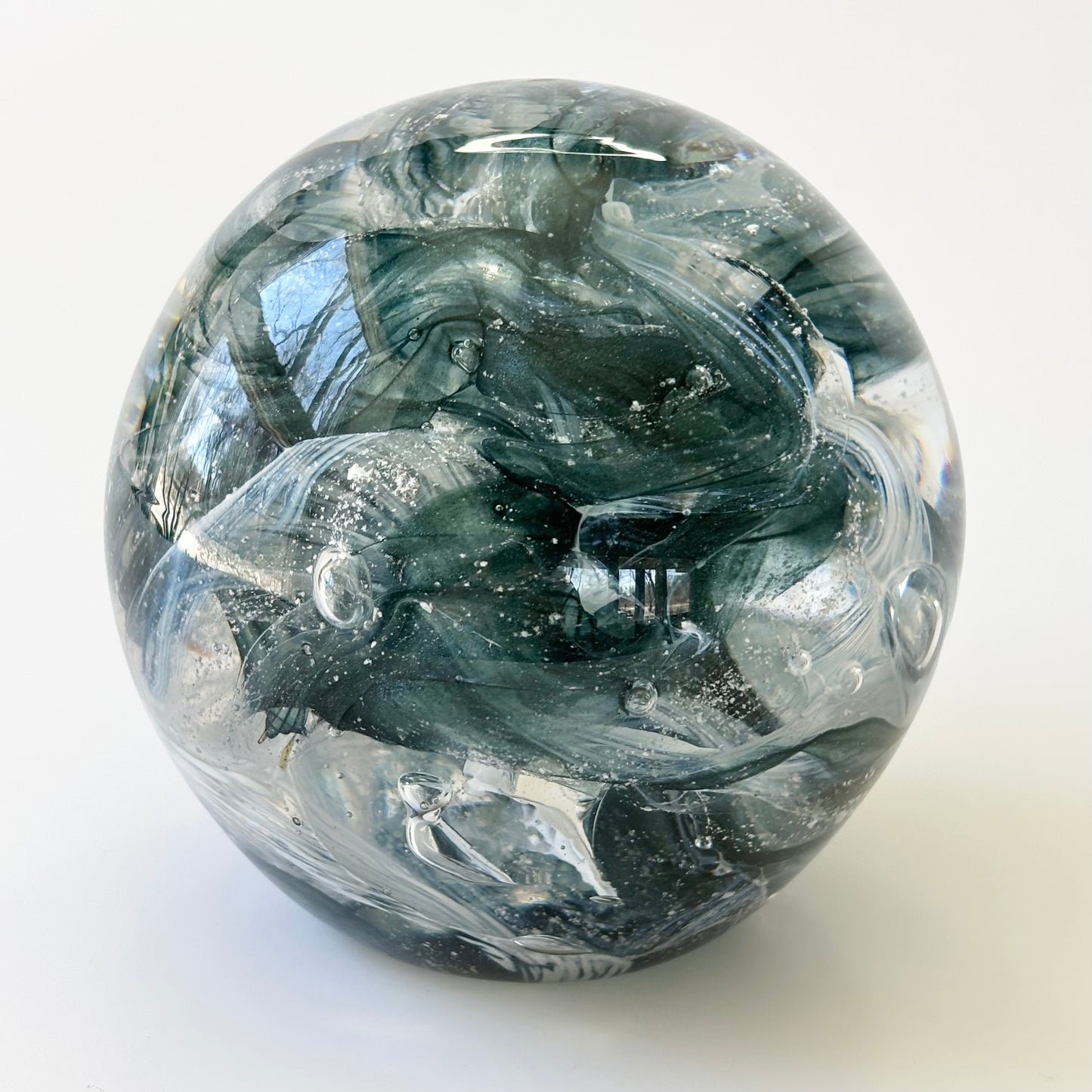 Artistic glass memorial with ribbon twist pattern design and infused cremation remains

