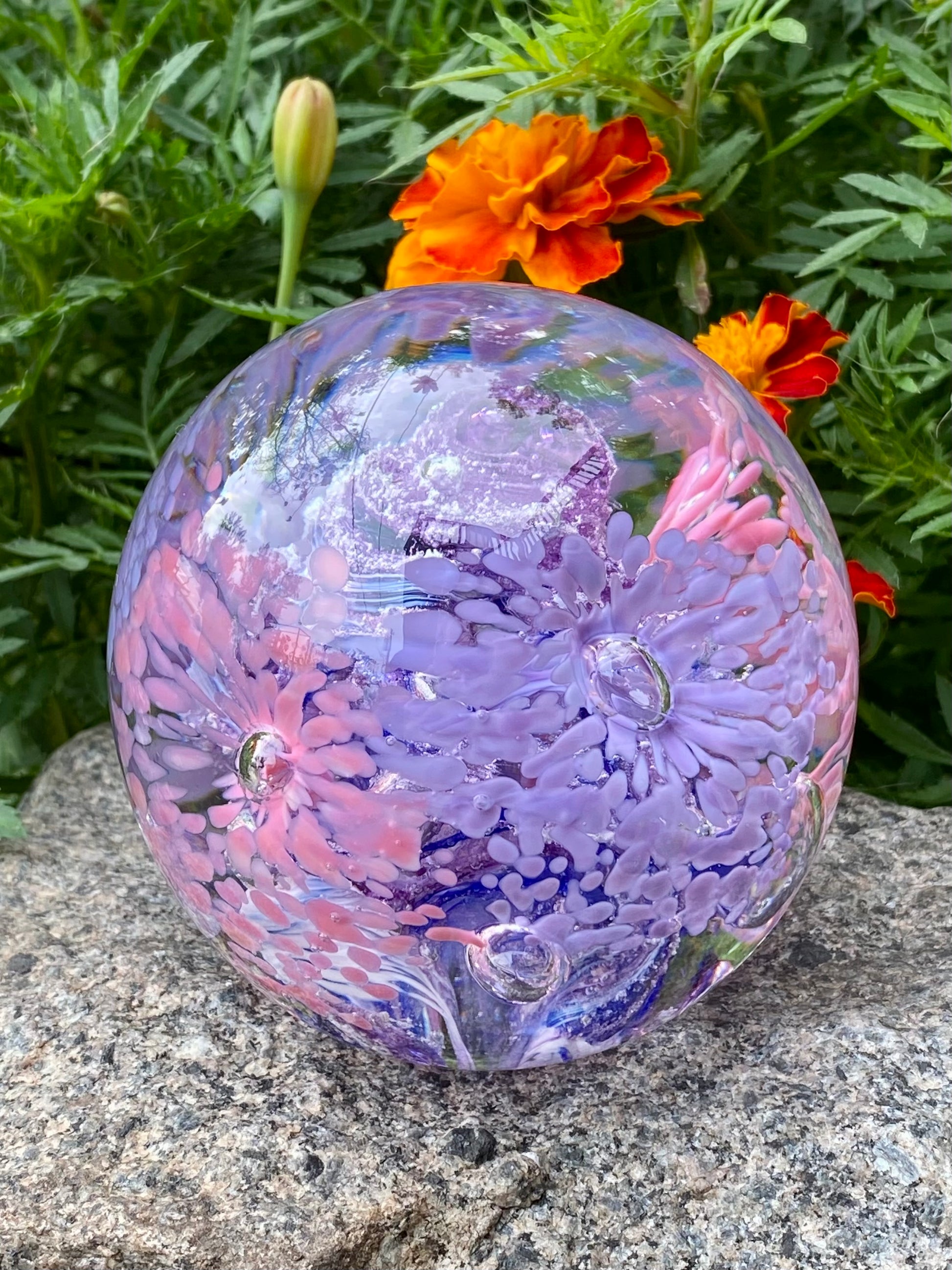 Eternal garden memorial orb. Glass paperweight with pink and purple flowers, ashes swirled in the center 

