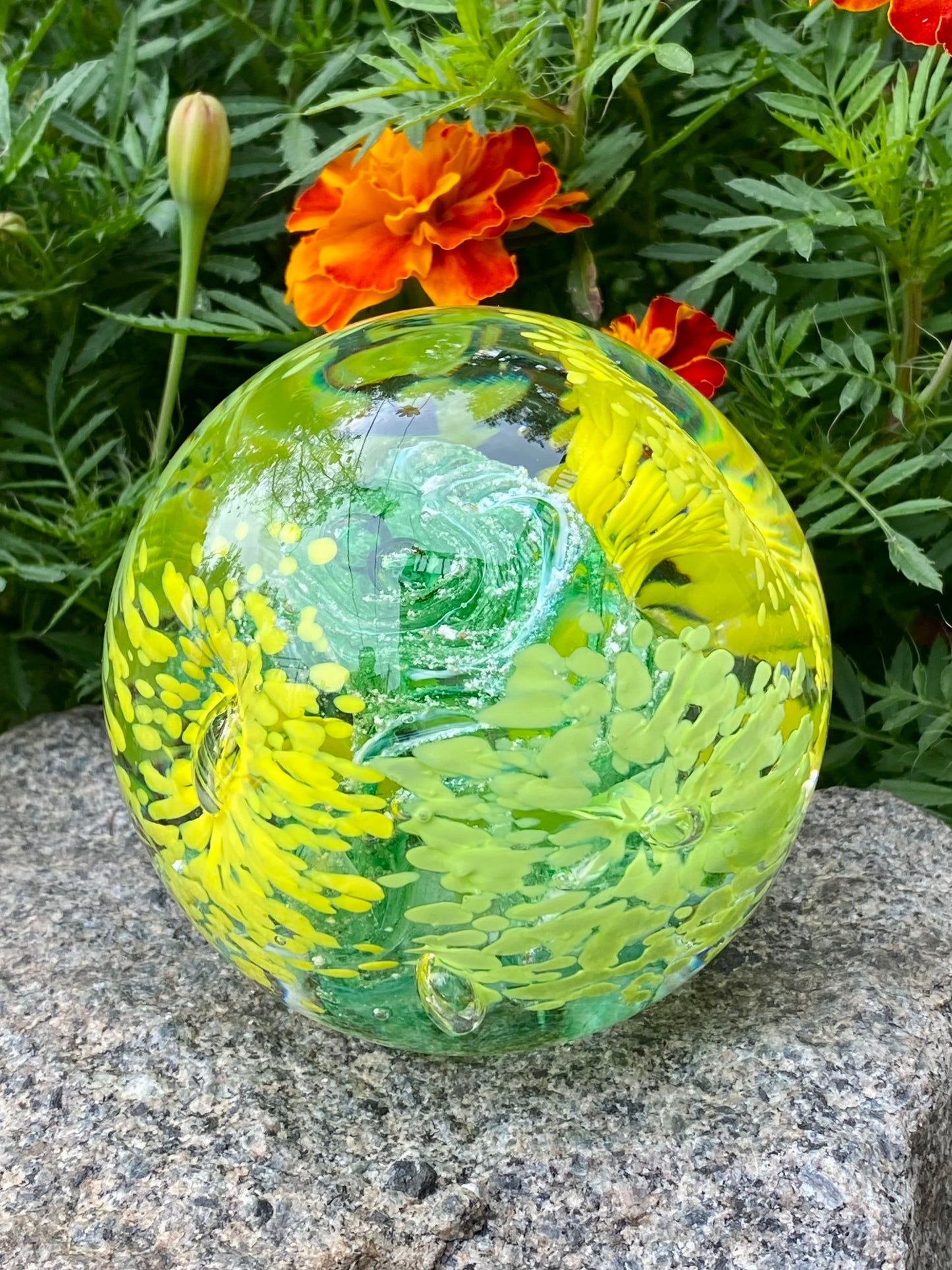Custom glass memorial paperweight featuring four flower designs and vibrant swirling ashes with yellow and green