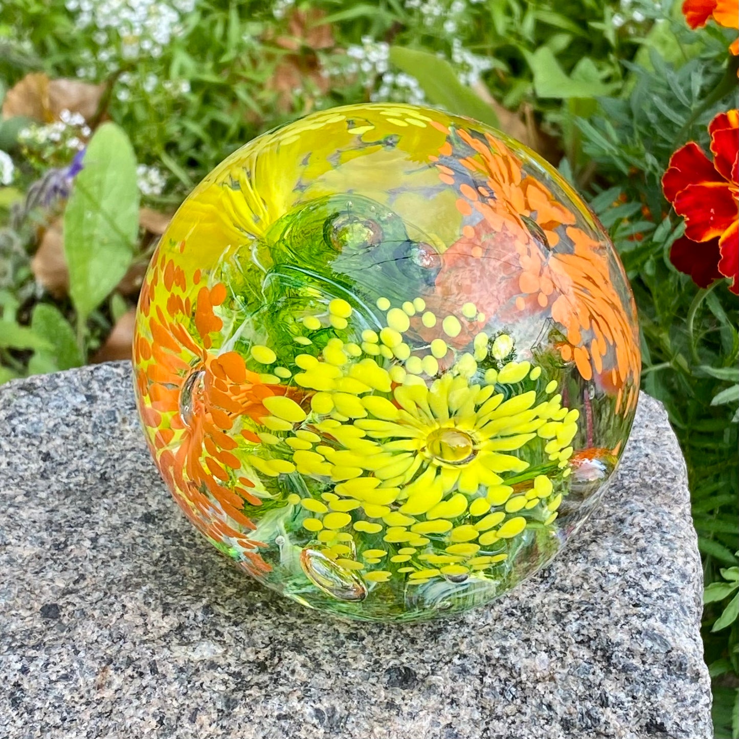 Eternal Garden memorial orb with layered glass flowers and cremation ashes in yellow orange and green center 