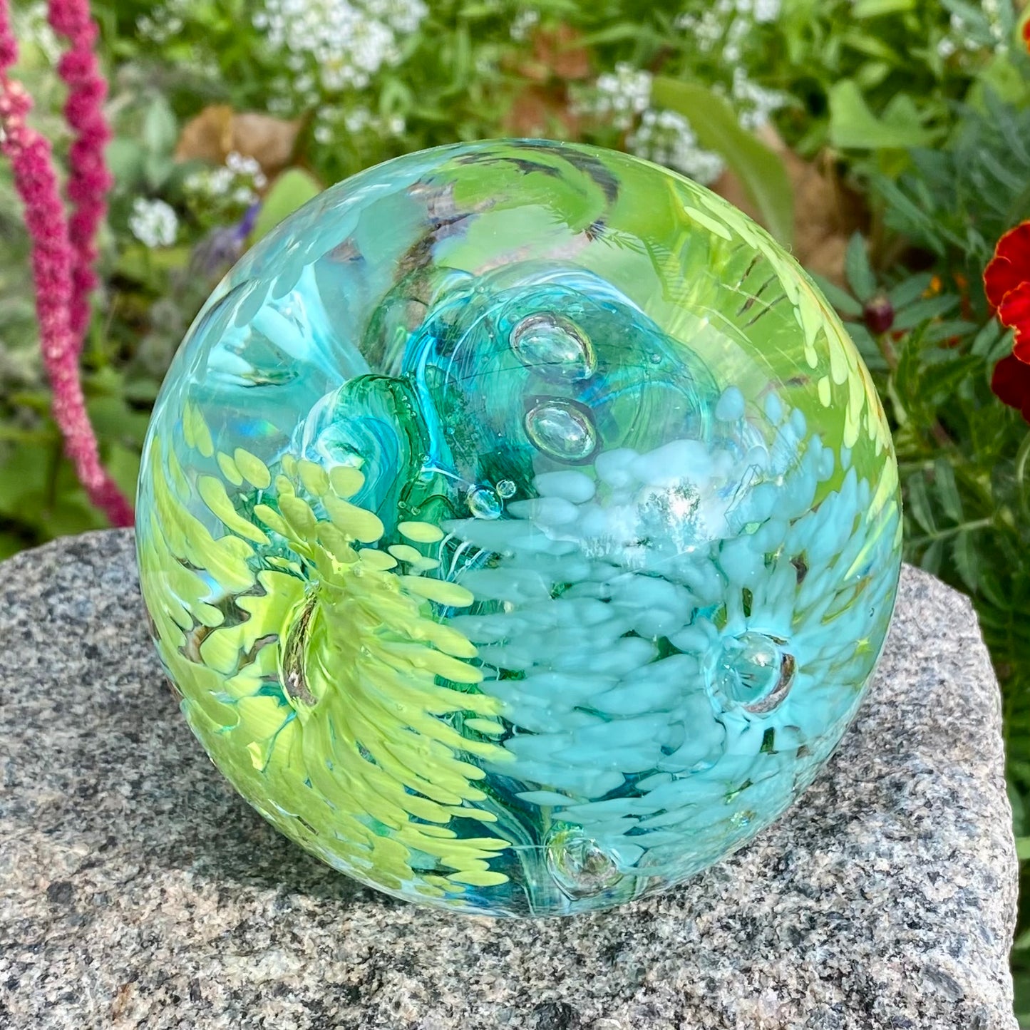 Handblown glass memorial orb with layered flower patterns and swirling colors of blues and greens