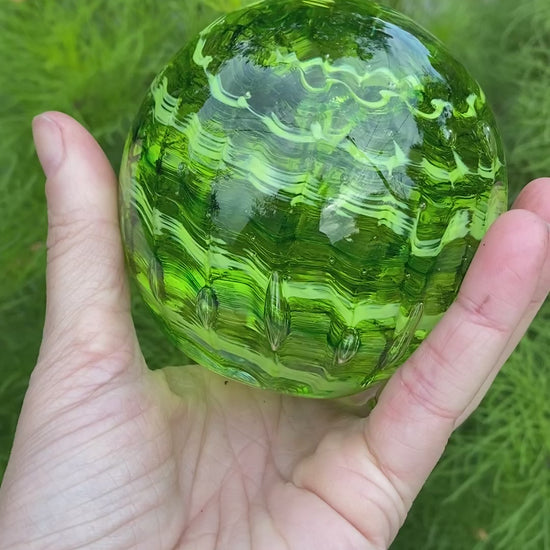 Handblown glass memorial orb with transparent and opaque green ripple swirl and cremation ash infusion