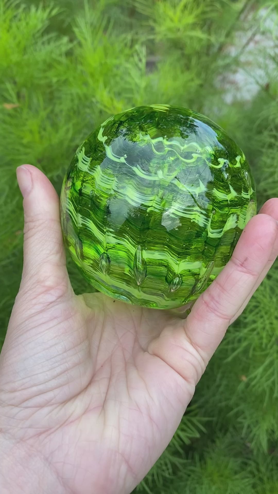 Handblown glass memorial orb with transparent and opaque green ripple swirl and cremation ash infusion