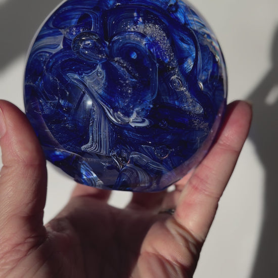 Cremation ash infused glass orb with aventurine blue sparkle and white ribbon twist pattern