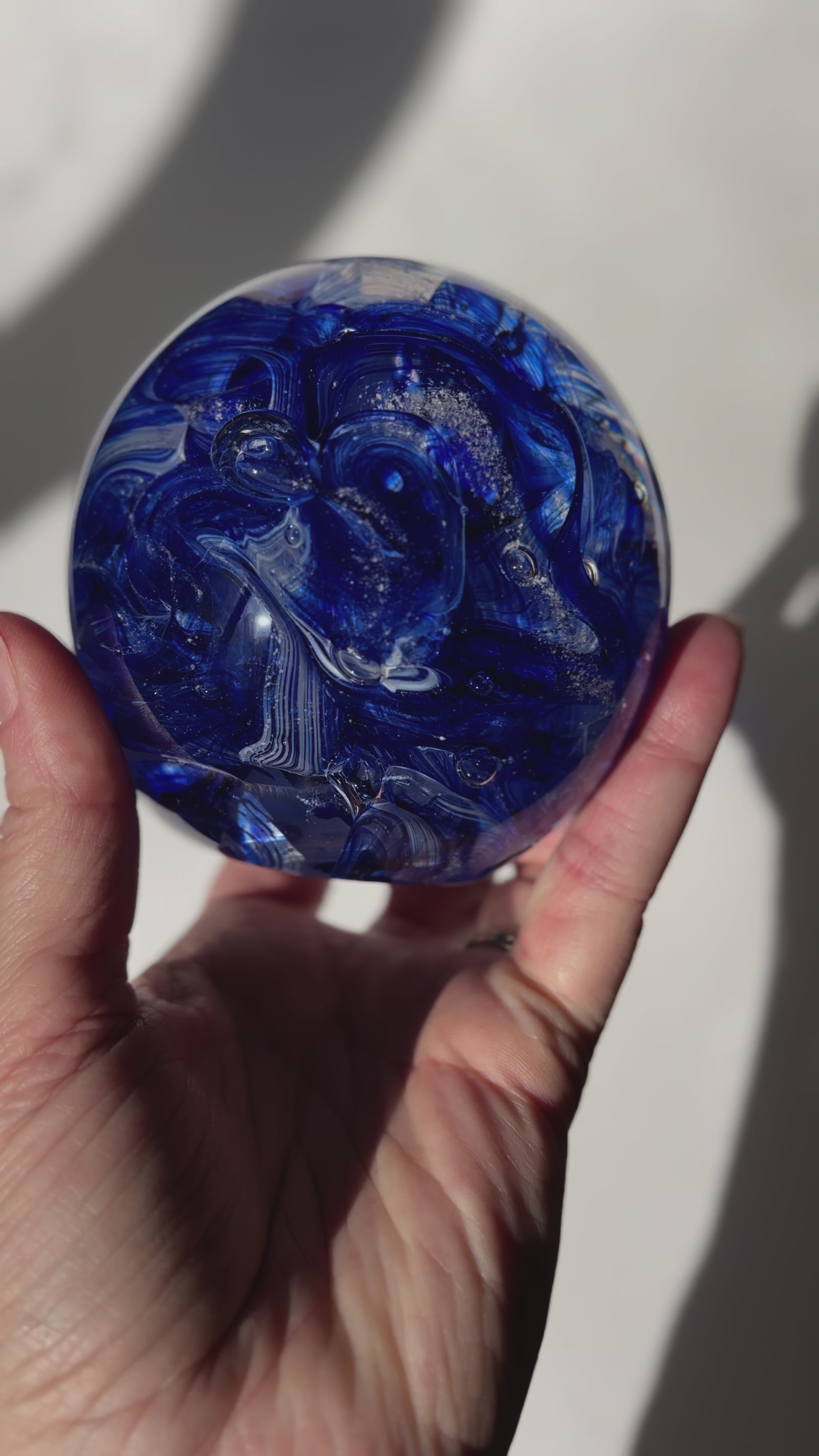Cremation ash infused glass orb with aventurine blue sparkle and white ribbon twist pattern