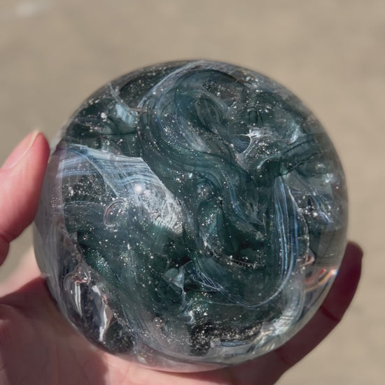Custom remembrance orb in aventurine pond glittering in the sun with ashes suspended in the core