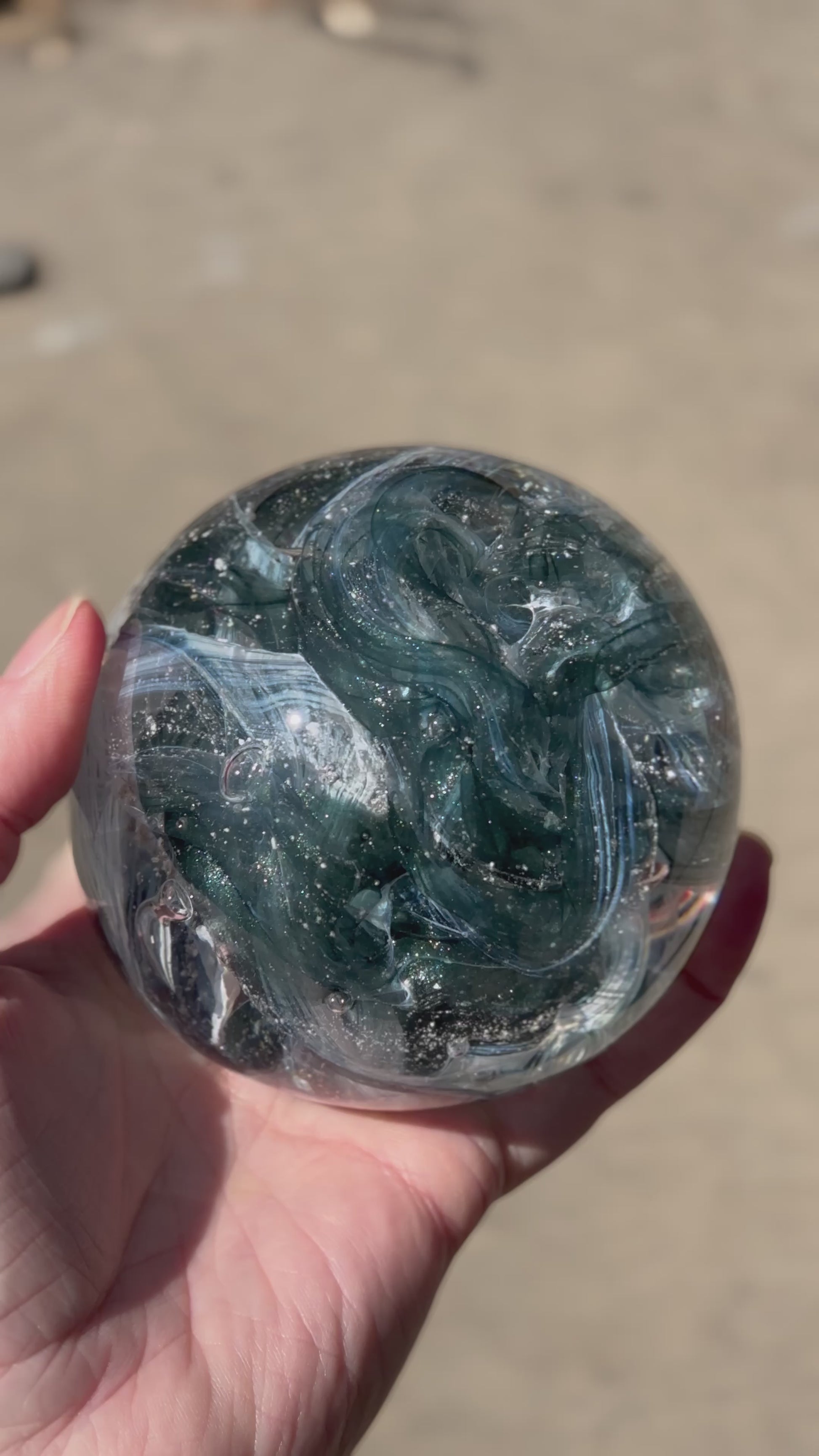 Custom remembrance orb in aventurine pond glittering in the sun with ashes suspended in the core
